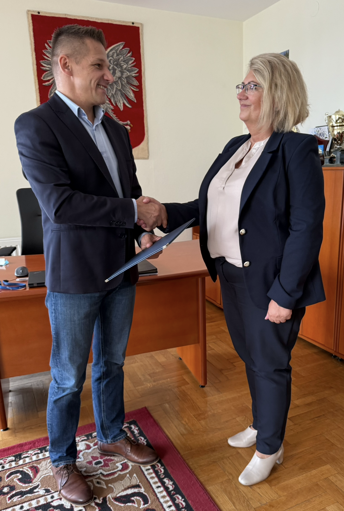 Kobieta i mężczyzna w pomieszczeniu. Składają sobie gratulacje. 