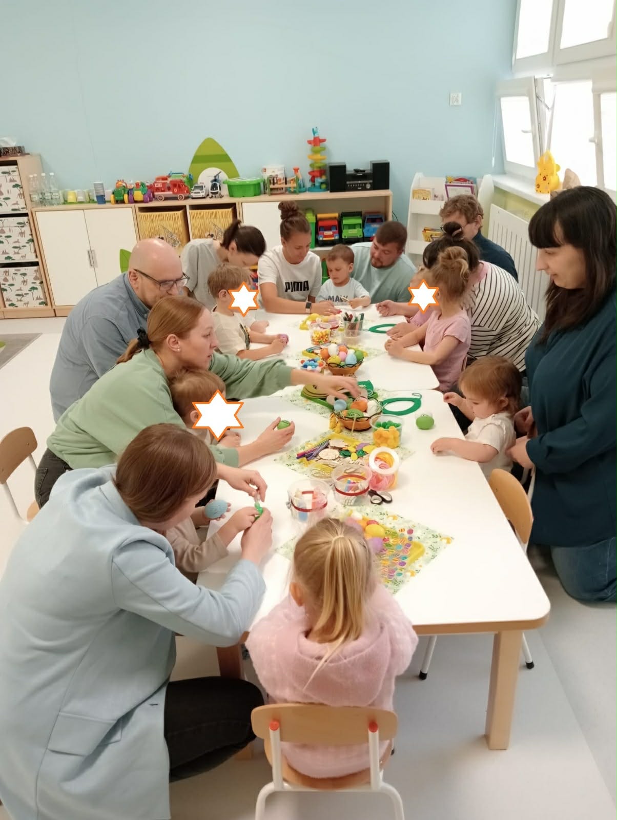 W pomieszczeniu siedzący rodzice z dziećmi podczas warsztatów wielkanocnych