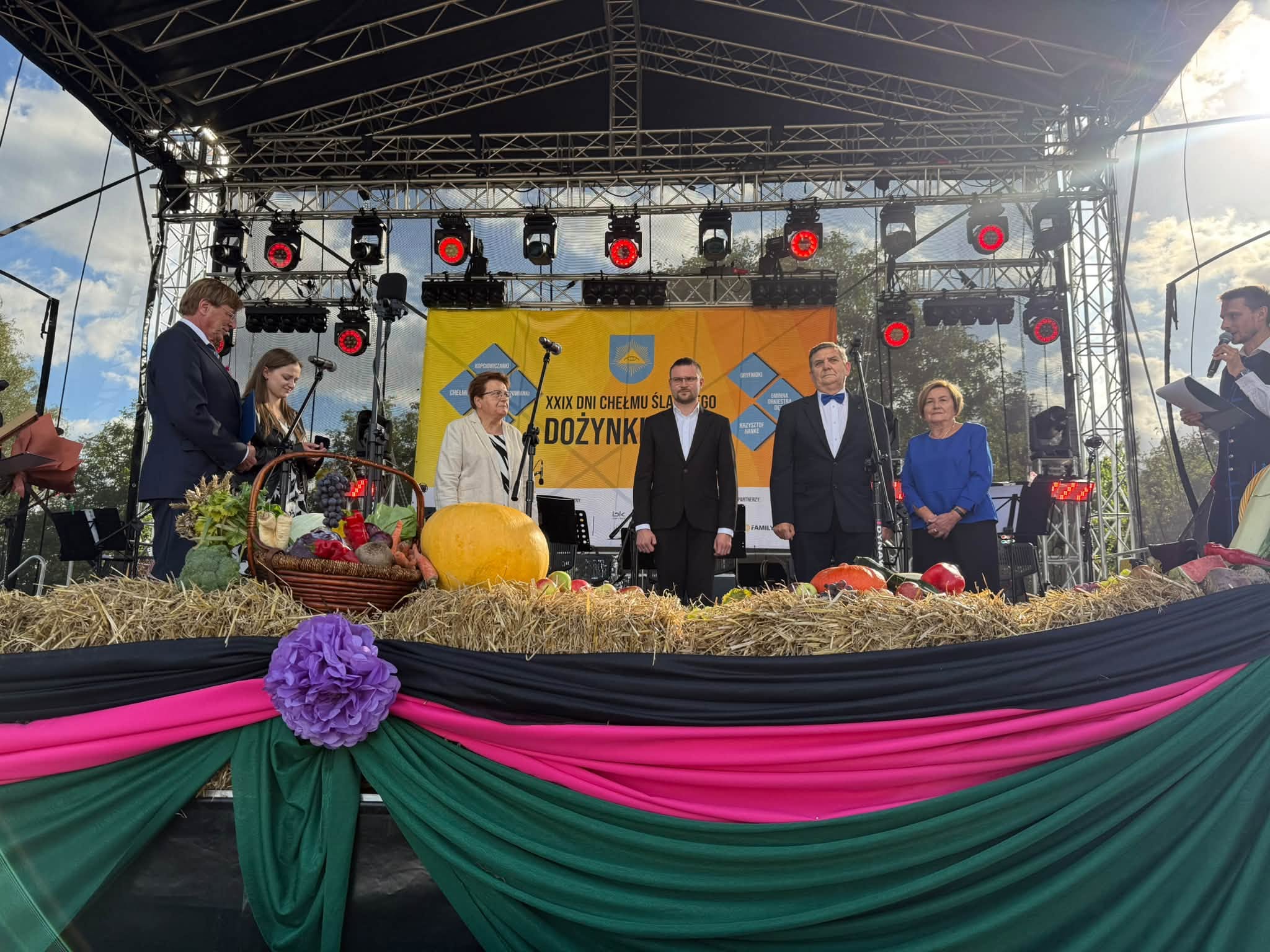 Osoby stojące na scenie plenerowej. 