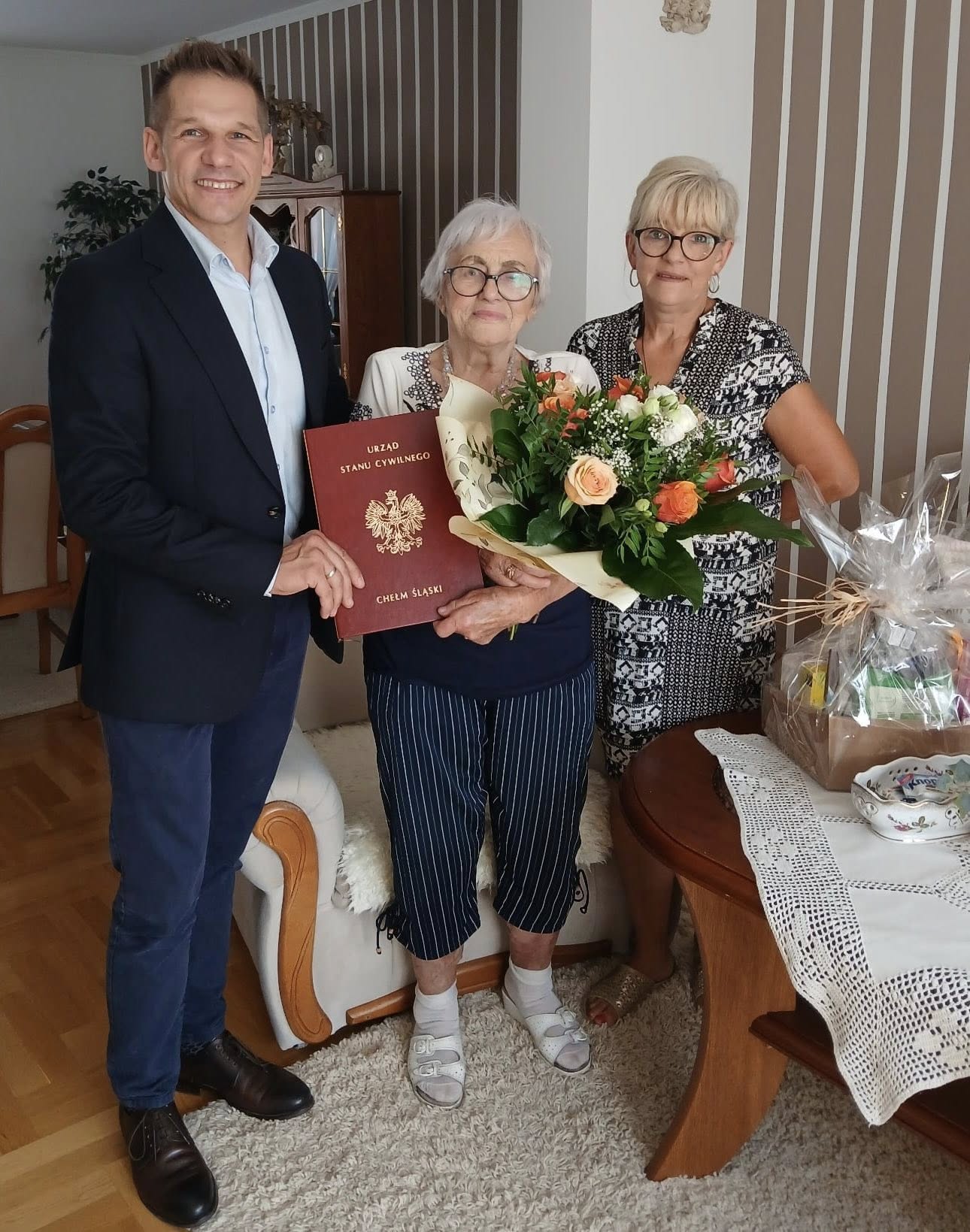 Osoby pozujące do zdjęcia z kwiatami i dyplomem