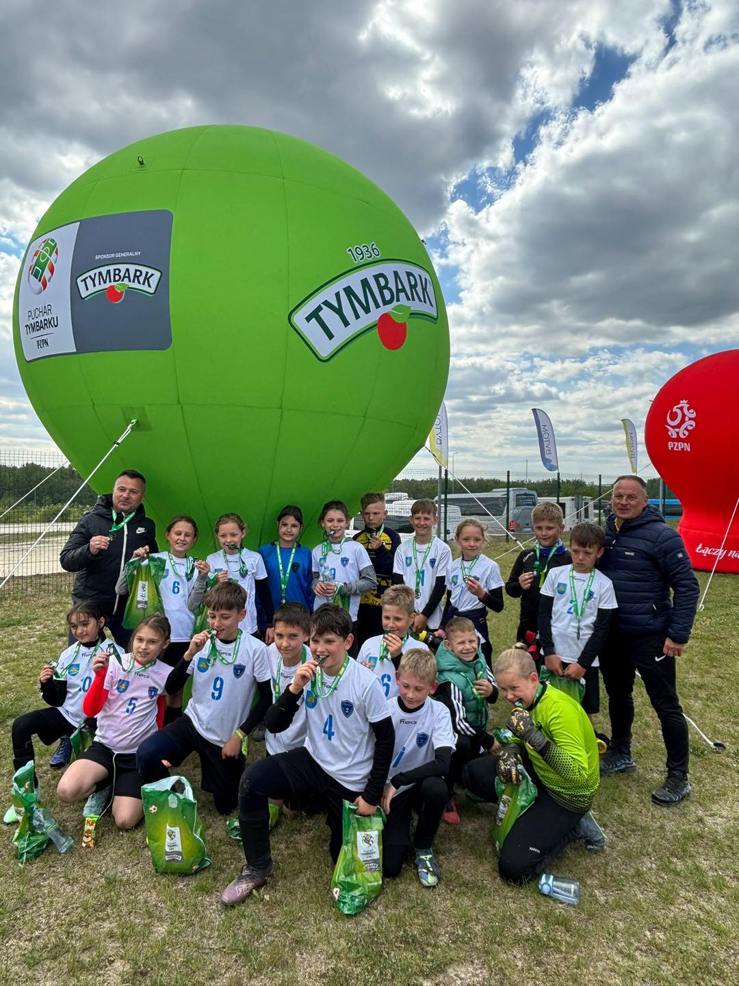 Balon z tymbarka i pozujące dzieci z opiekunami do zdjęcia. 