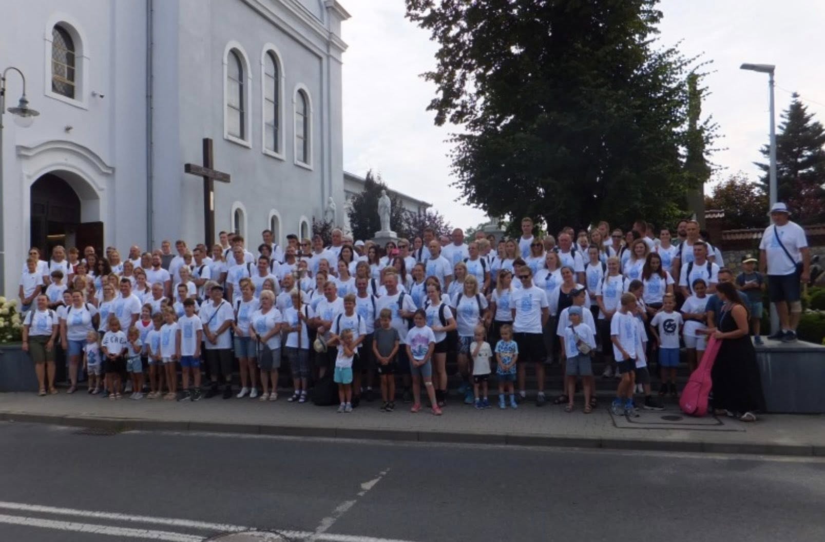 Osoby stojące na schodach przed kościołem 