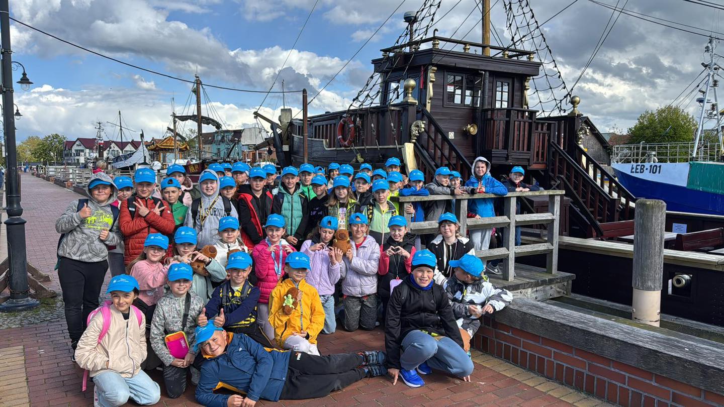 Dzieci stojące na keji pozujące do zdjęcia przed statkiem 