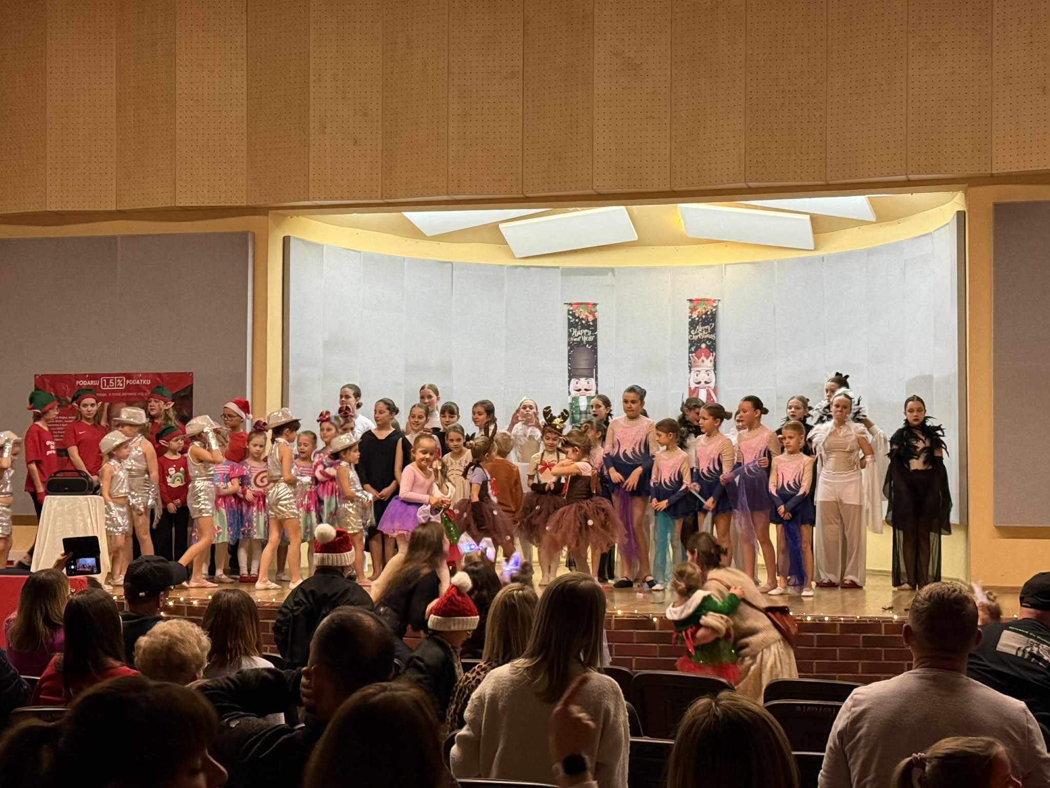 Dzieci stojące w kolorowych strojach na scenie 