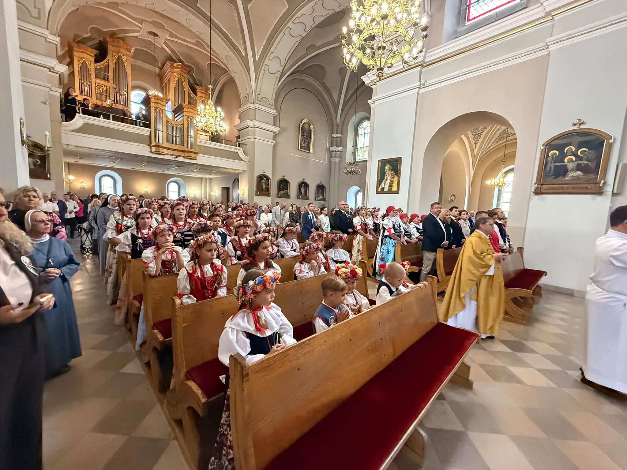Ludzie w kościele, dzieci w strojach ślaskich 