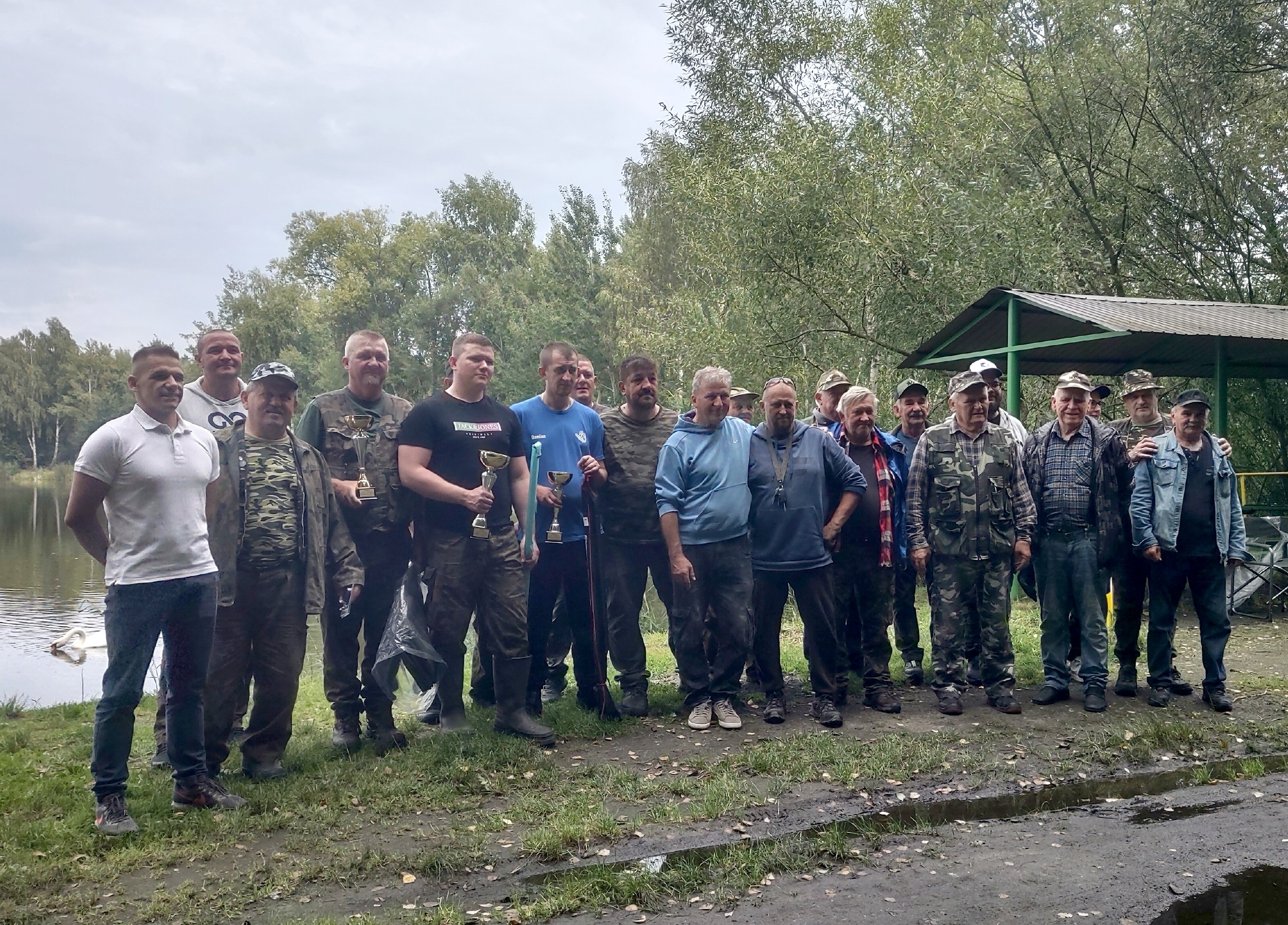 Mężczyźni pozujący do zdjęcia nad brzegiem stawu