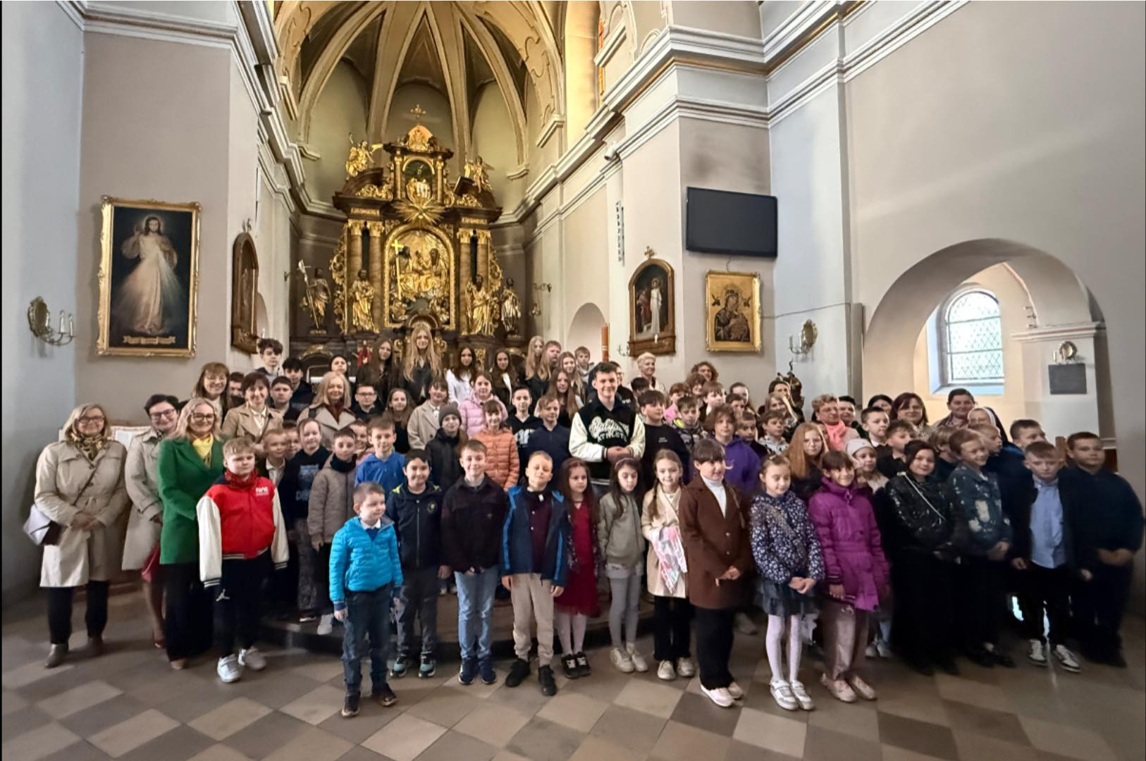 Dzieci i dorośli pozujacy do zdjęcia w tle ołtarza