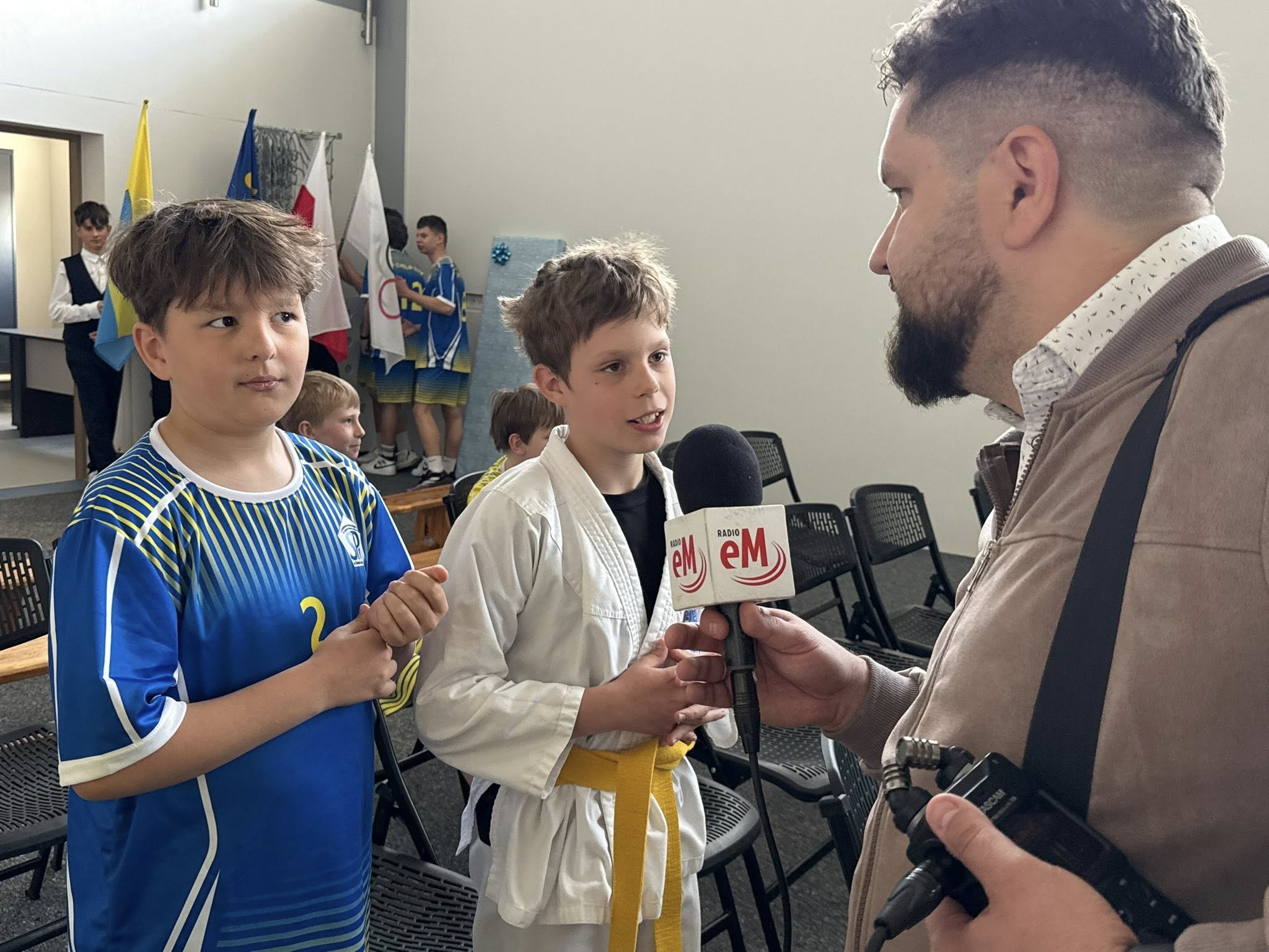 Mężczyzna z radia eM rozmawiający z dwoma chłopakami w pomieszczeniu. 