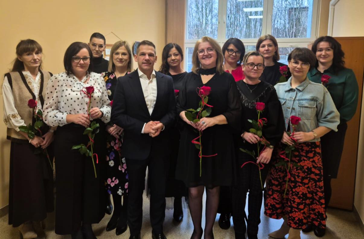 Mężczyzna i kobiety z kwiatami pozujące do zdjęcia w pomieszczeniu 