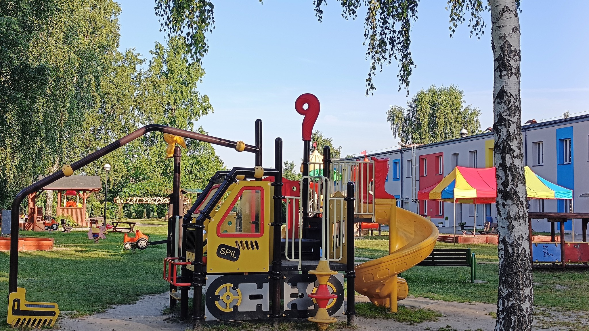 Plac zabaw dla dzieci przy przedszkolu. Na zdjeciu urządzenia do zabaw dla dzieci. 