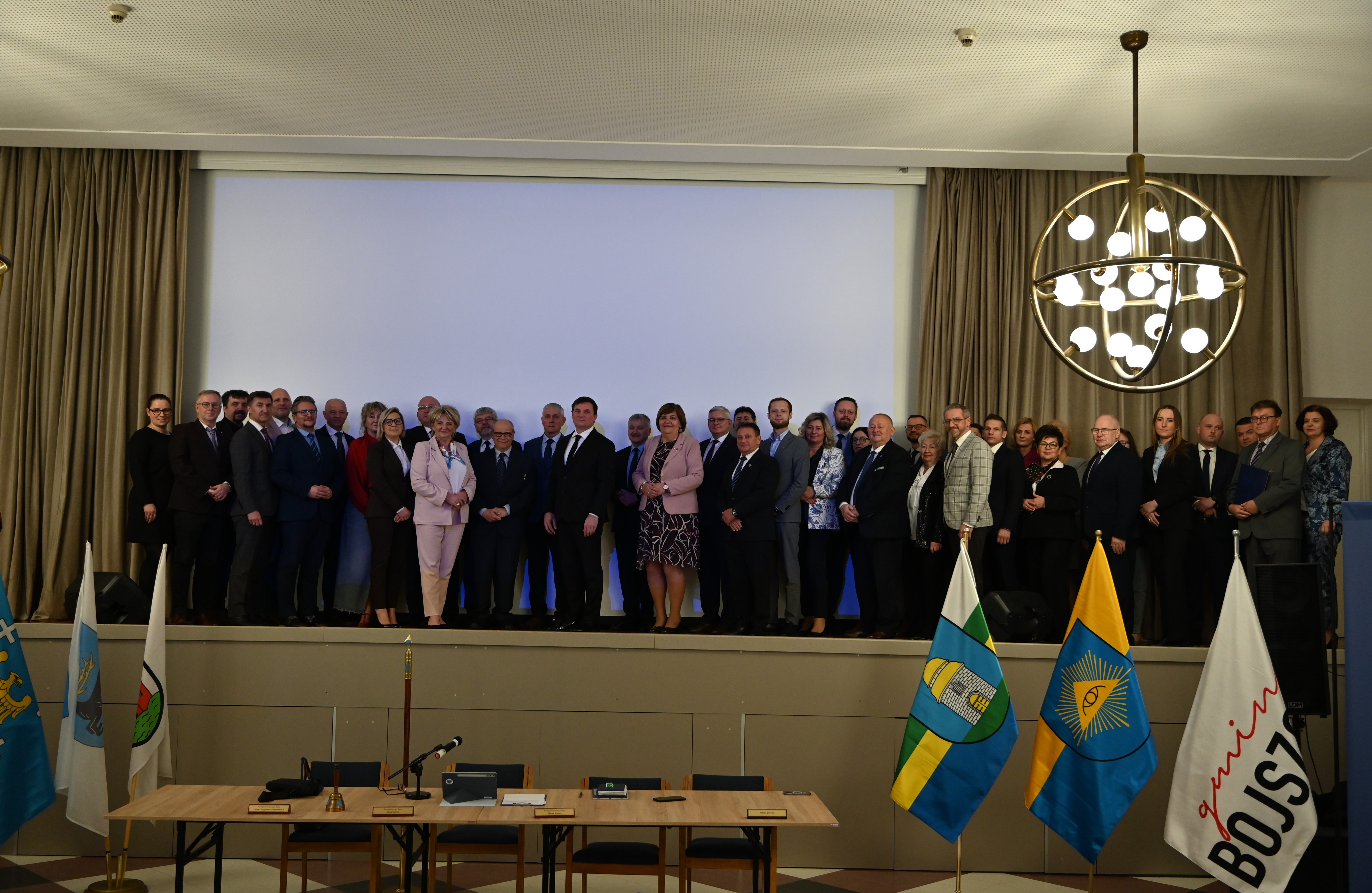 Uczestnicy sesji Rady Powiatu w pomieszczeniu pozujący do zdjęcia. 