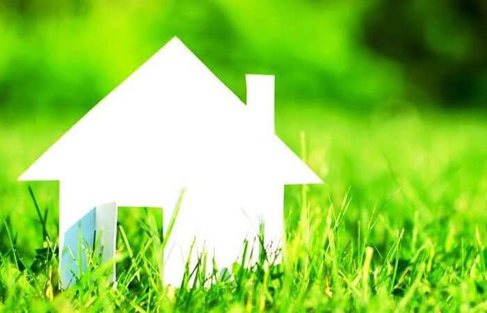 Na zielonej trawie biały domek 