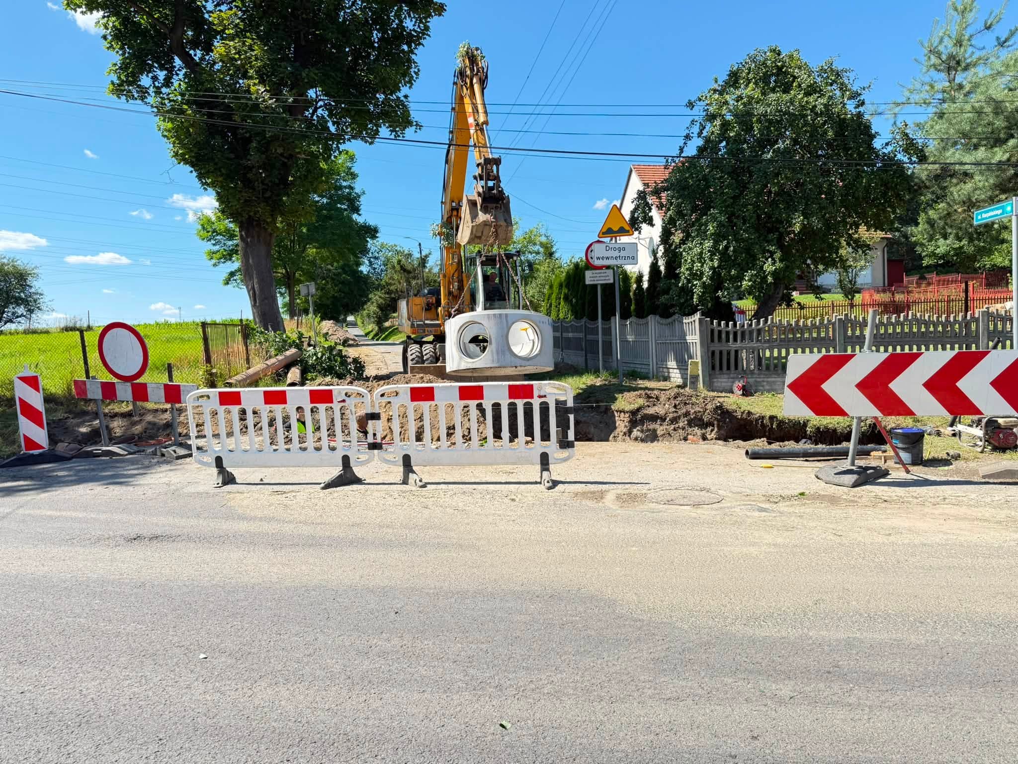 Teren prac w terenie. Na pierwszym planie koparka montująca kolektor - wprowadzająca kolektor do wykopu 