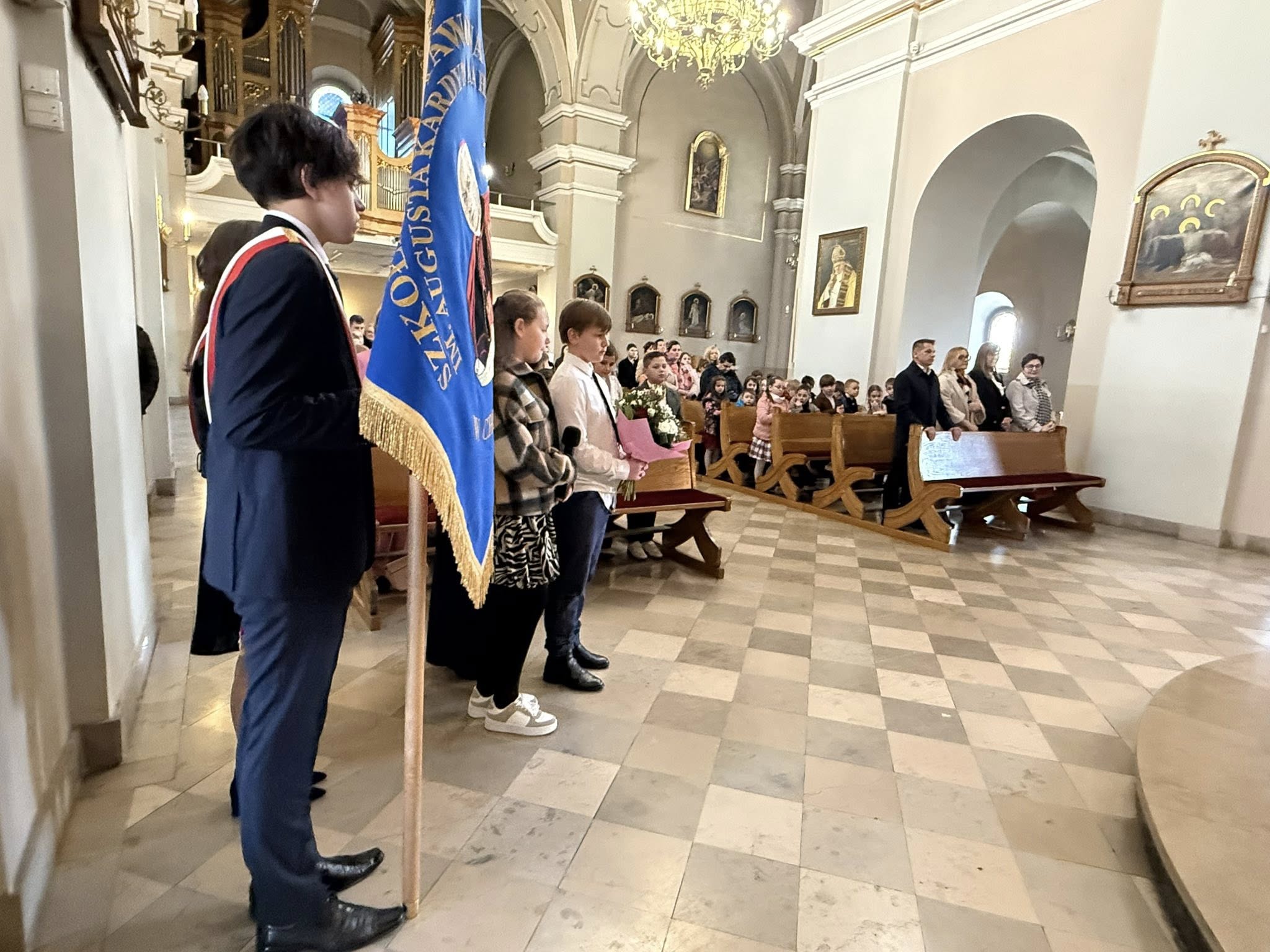 Uczestnicy mszy w kościele - na pierwszym planie po lewej stronie młodzież ze sztandarem szkoły. 