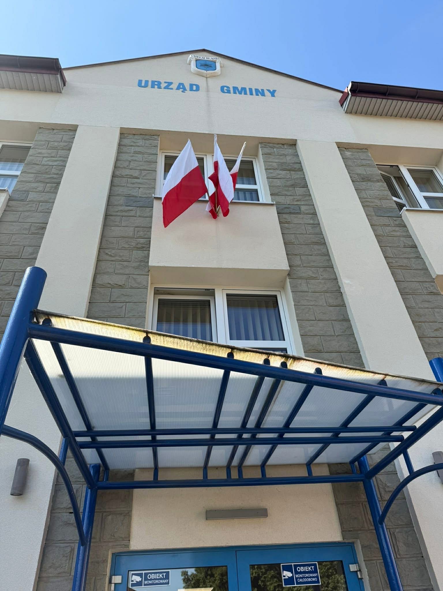 Budynek Urzędu Gminy z powiewającymi flagami 