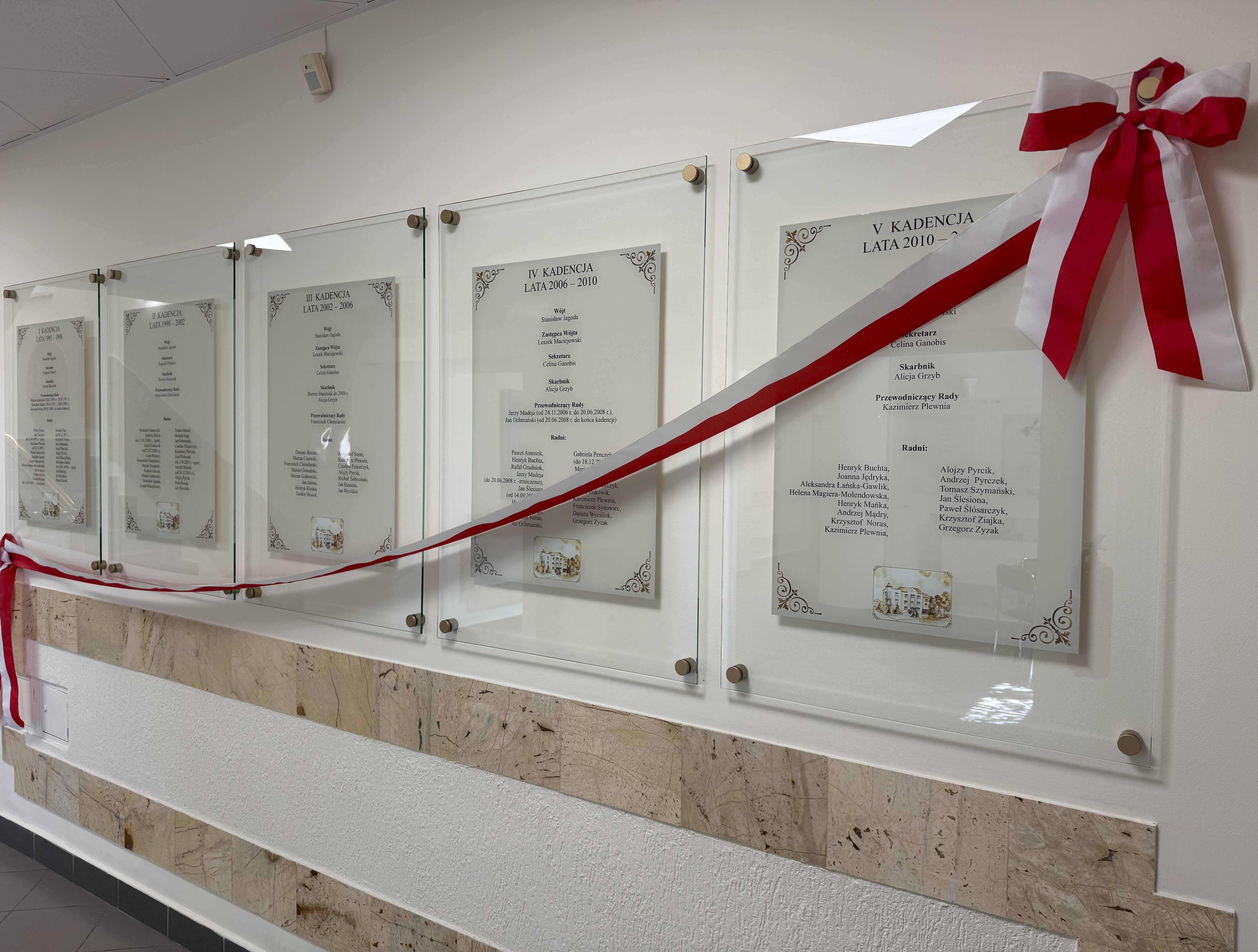 Tabla wiszące na ścianie, przepasane biało - czerwoną szarfą,