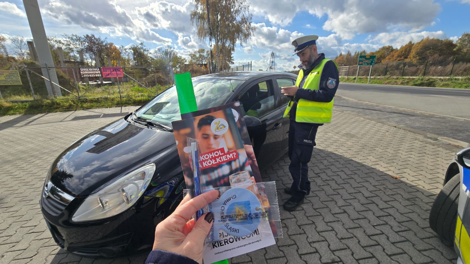 Policjant kontolujacy pojazd. na pierwszym planie materiały edukacyjne