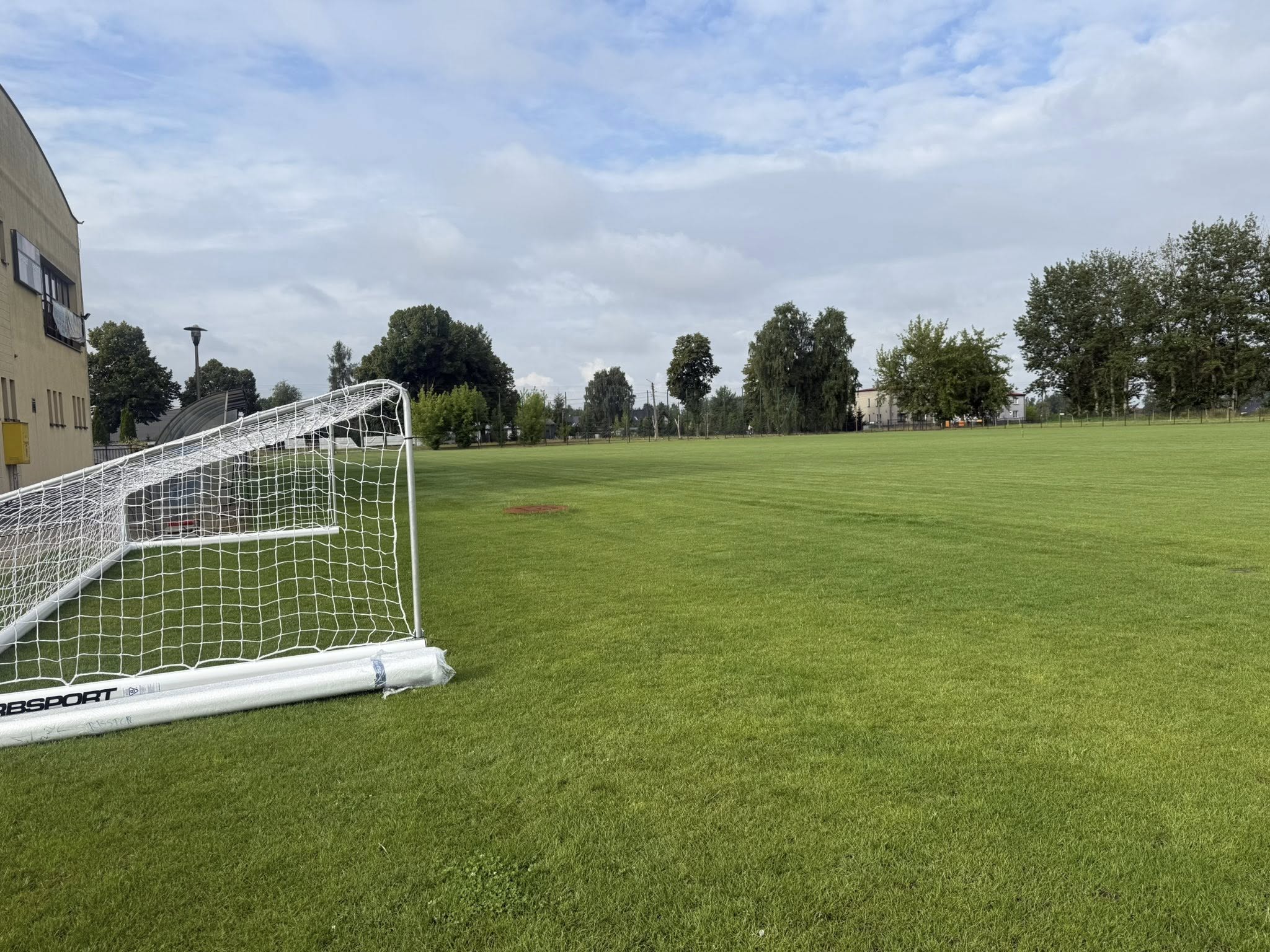 Muraw boiska piłkarskiego i leżąca bramka przy budynku