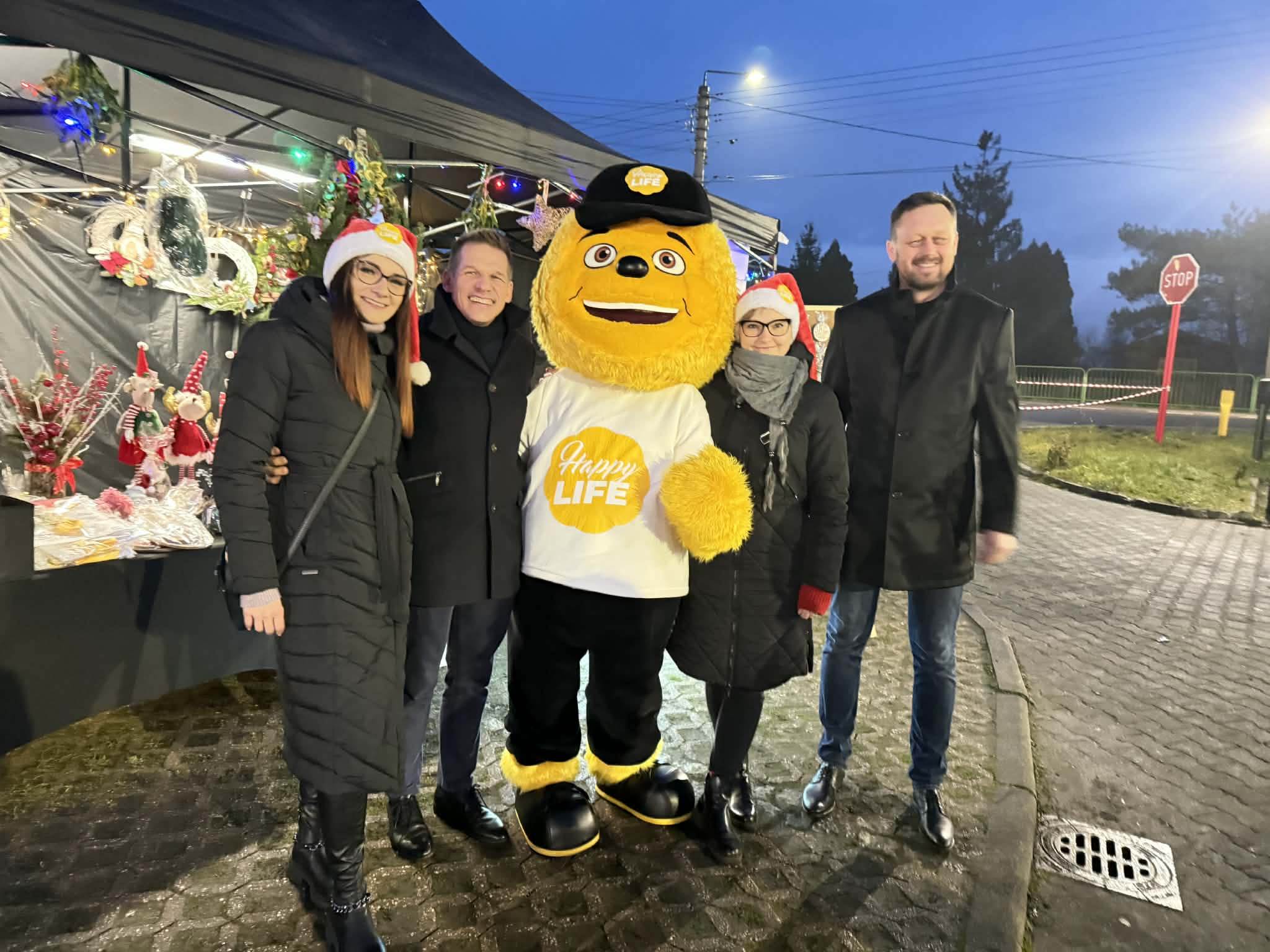 Osoby pozujące do zdjęcia z maskotką fundacji Happy Life 