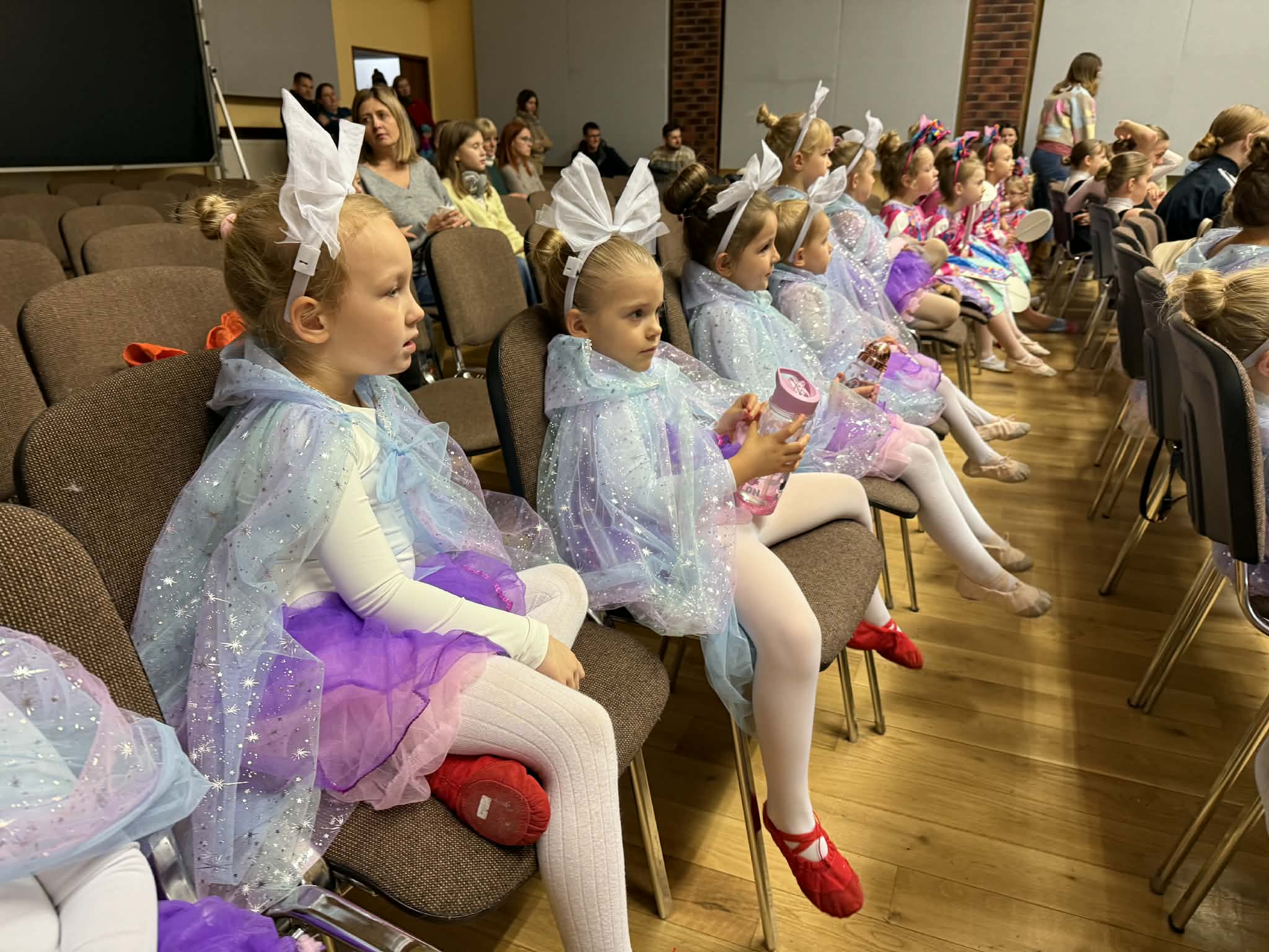 Dzieci siedzące na krzesłach w kolorowych strojach 