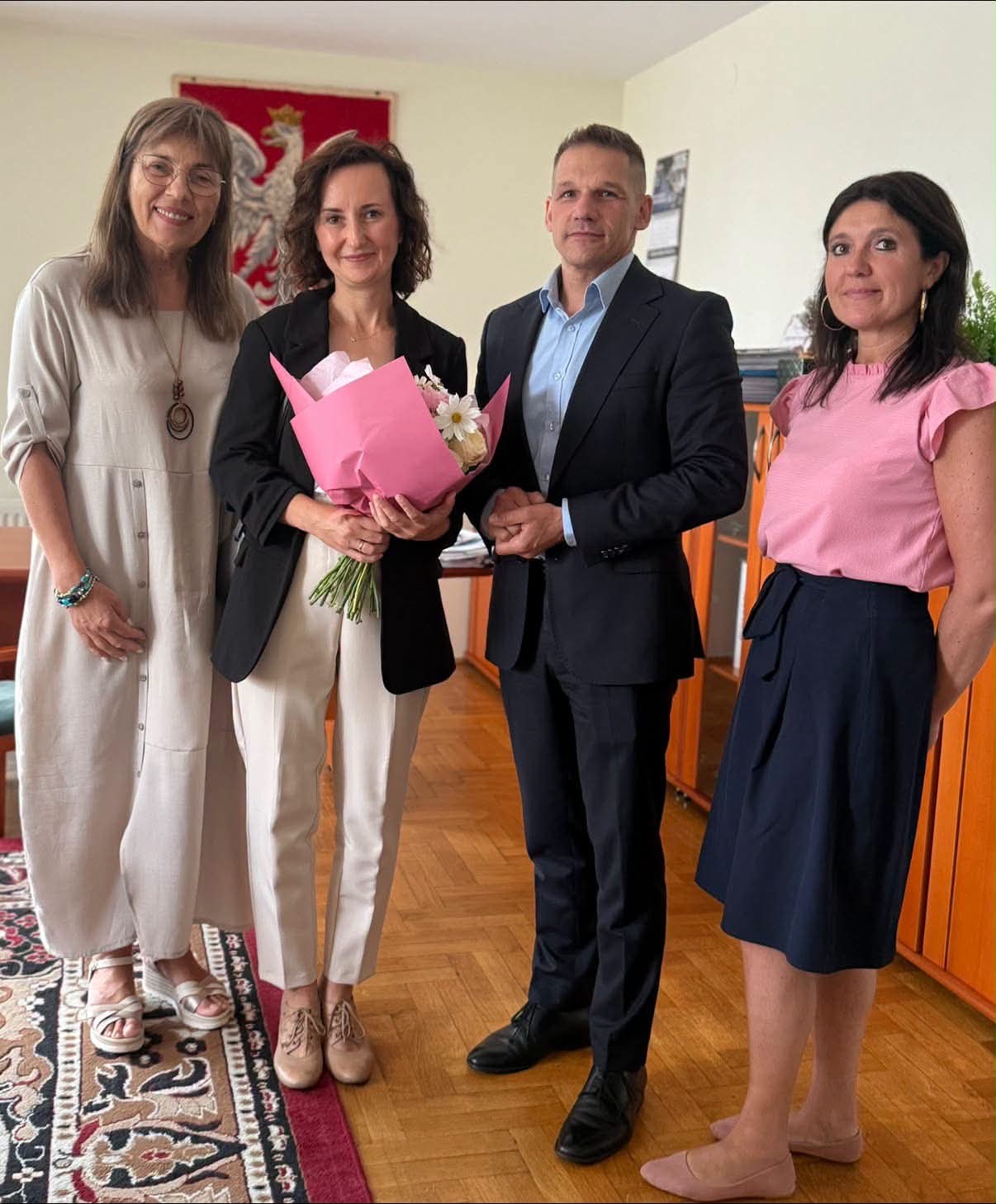 Trzy kobiety i mężczyzna pozujacy w pomieszczeniu do zdjęcia. 