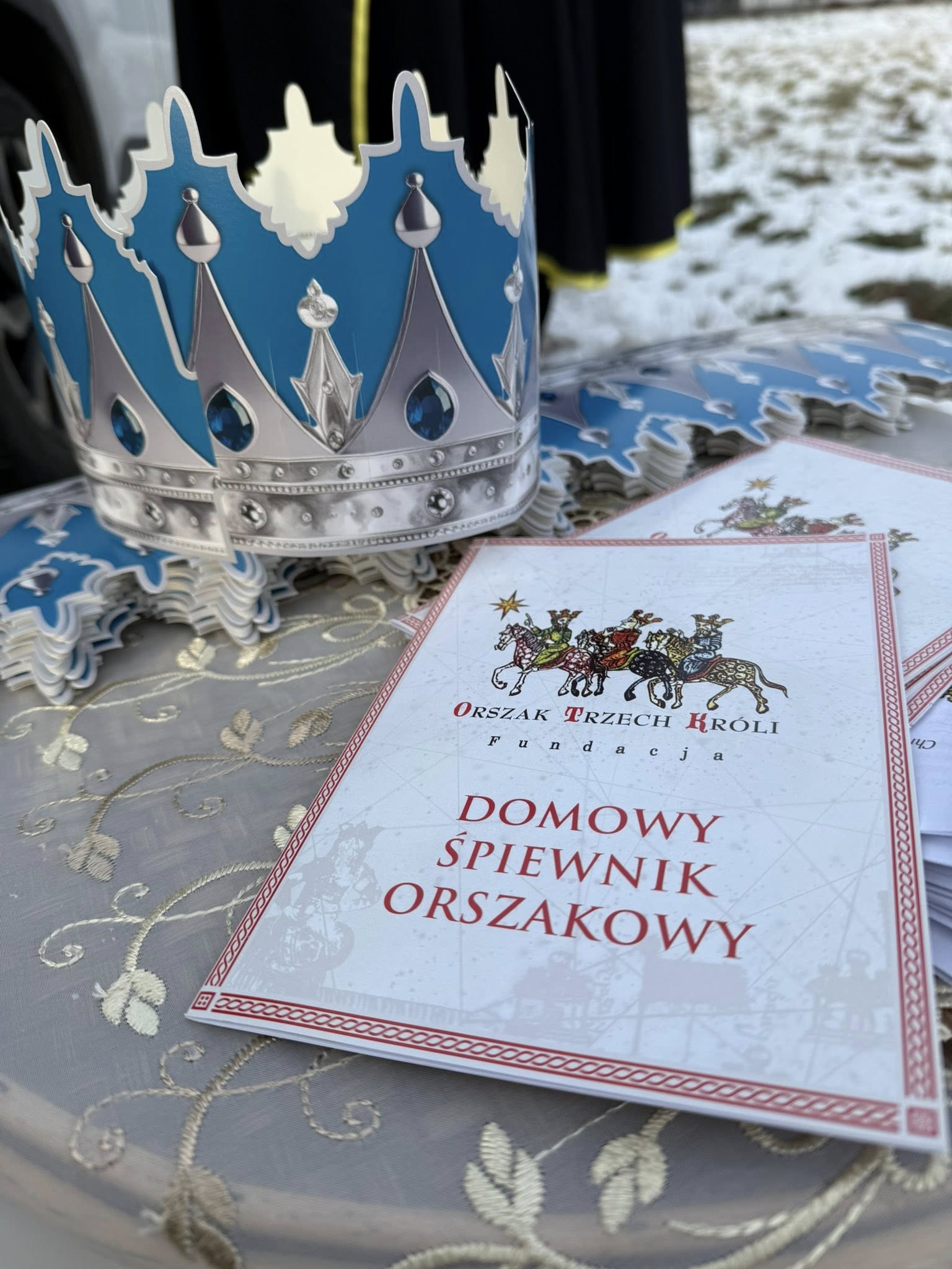 Korona w kolorach niebiesko srebrnych i okładka spiewnika Orszaku Trzech Króli 