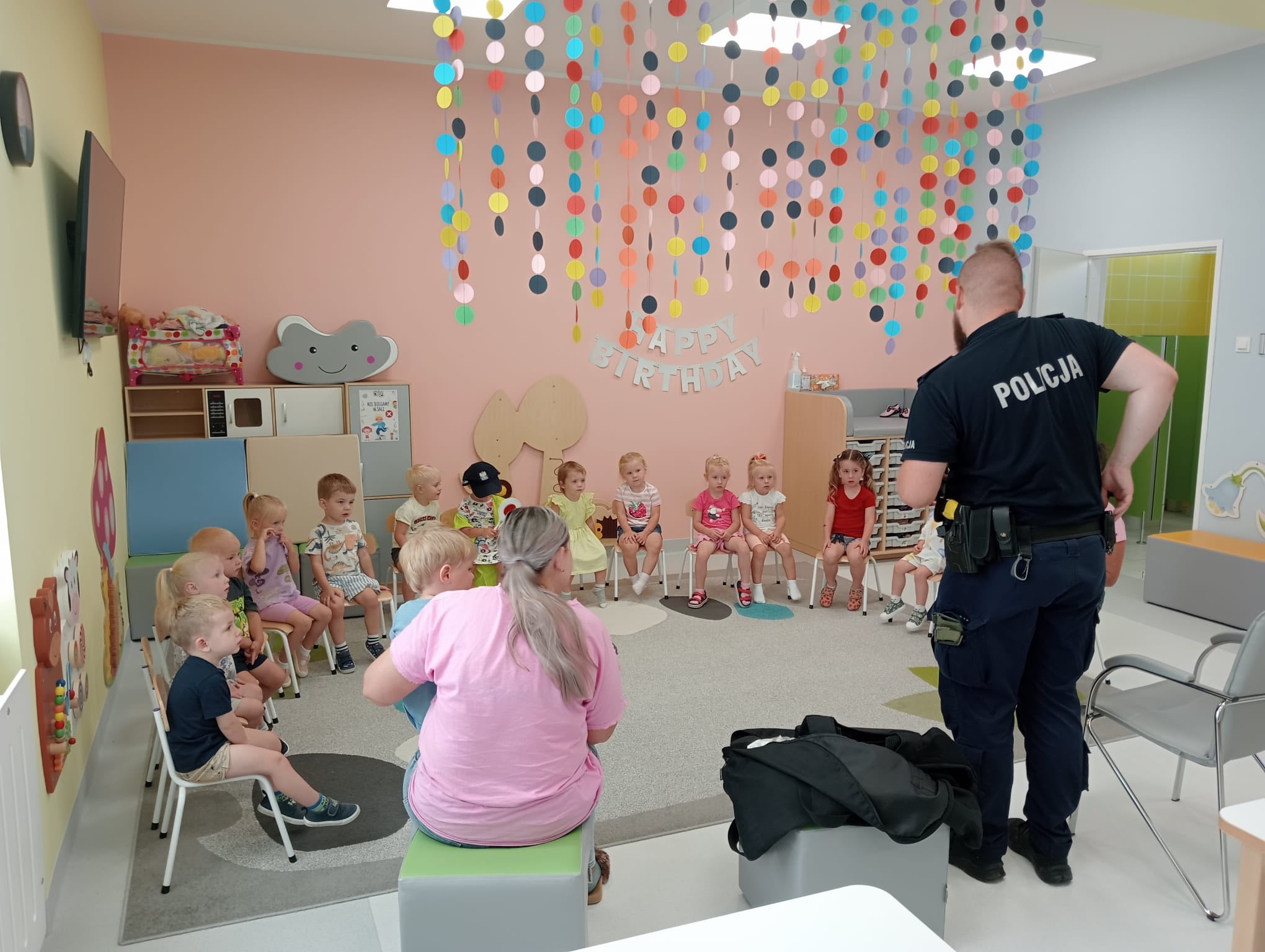 Dzieci siedzące w sali i policjant 