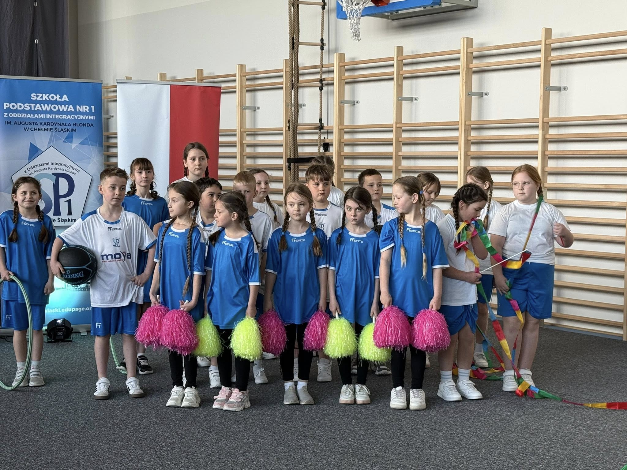 Dzieci w strojach sportowych z pomponami w dłoniach 